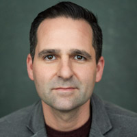 Michael French football coach and director at We Make Footballers NW London, member of The Tutor Collective, professional headshot in grey suit jacket.